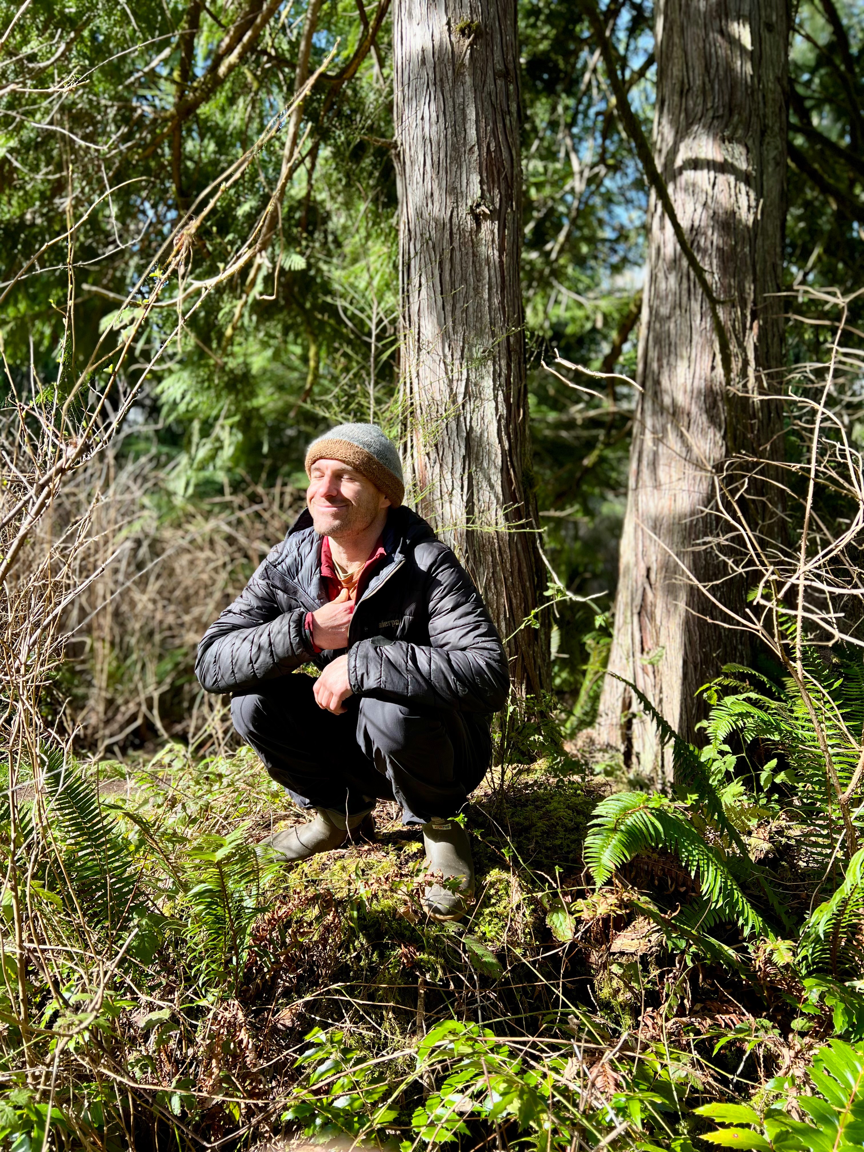 Lee in nature, hand on heart, connecting with the forest